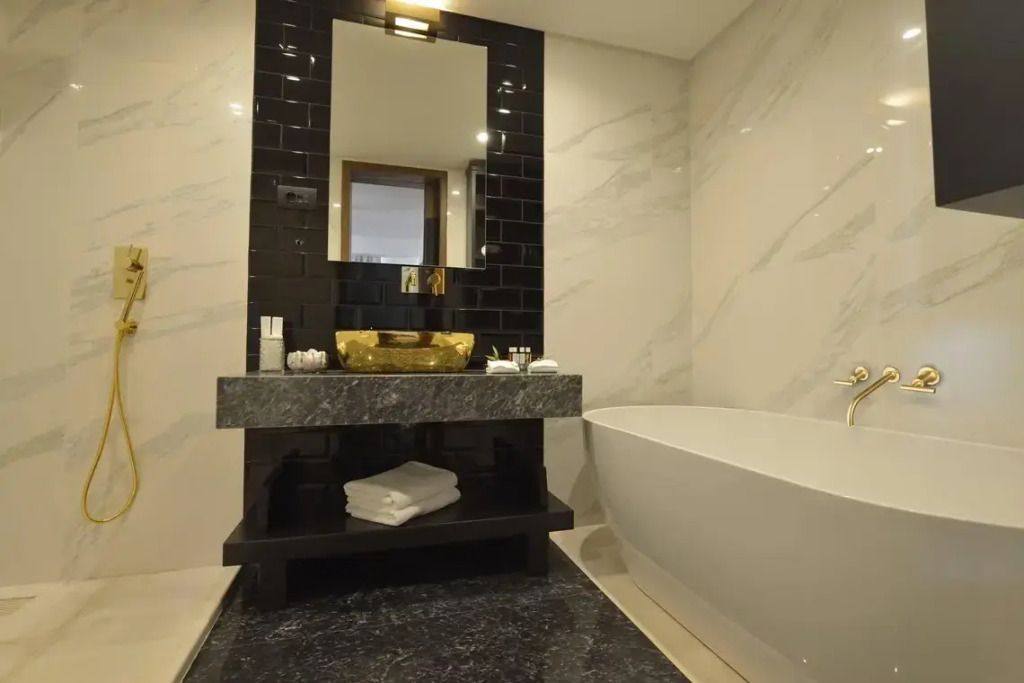 Modernes Bad mit freistehender Badewanne und goldenen Armaturen