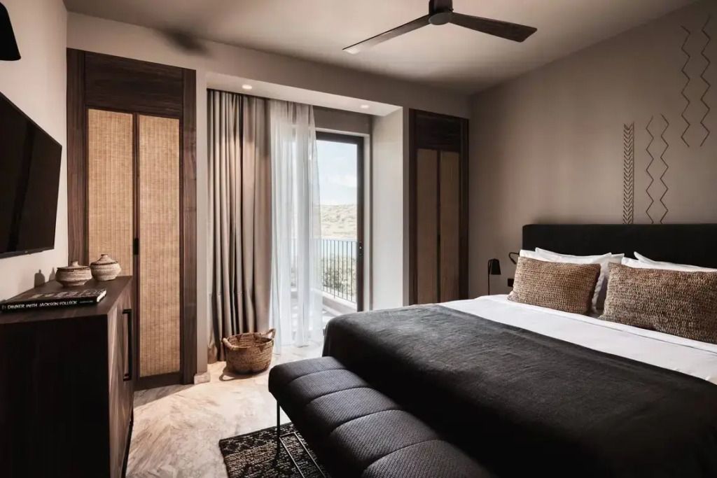 Helles Hotelzimmer mit großem Bett und Meerblick vom Balkon