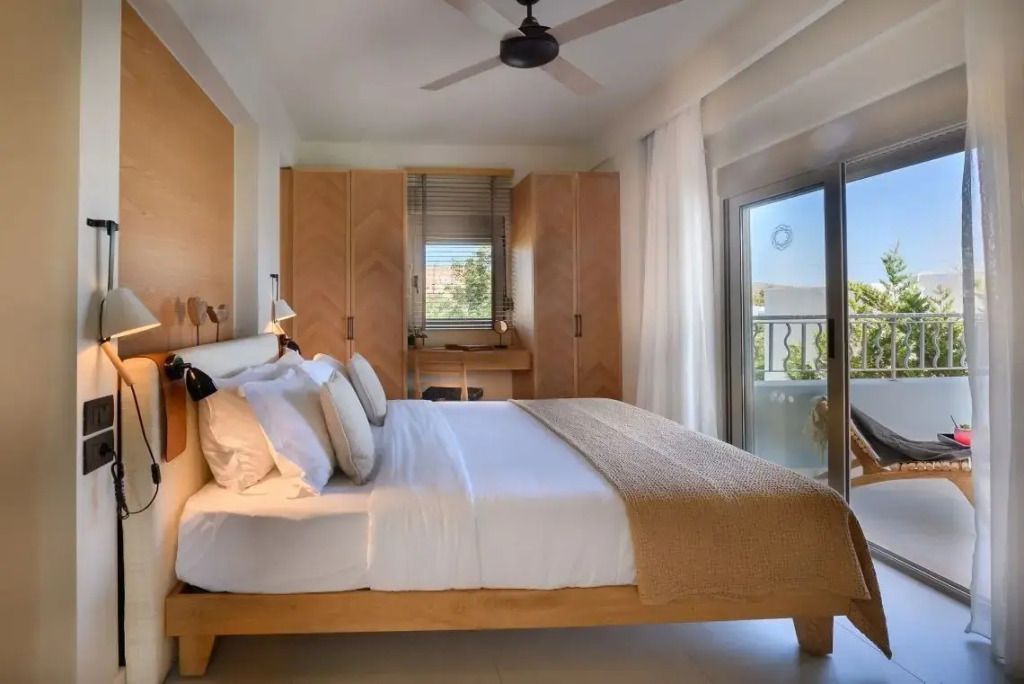 Helles Schlafzimmer mit großem Bett und Balkon mit Meerblick im Domes of Elounda