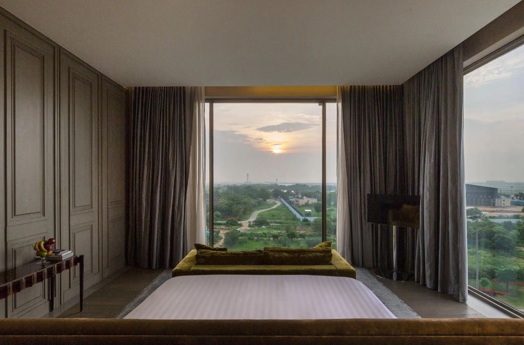 Schlafzimmer mit großem Panoramafenster und Sonnenuntergang