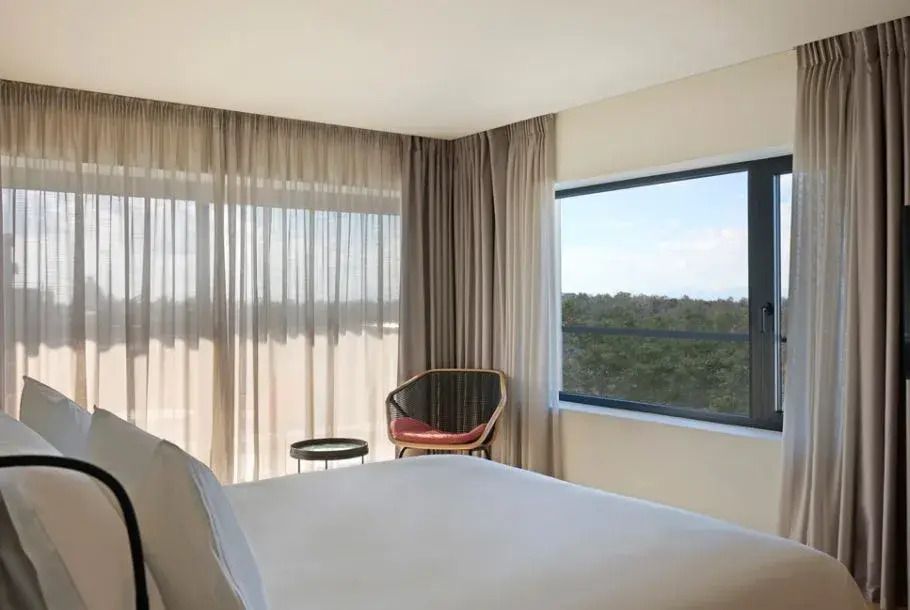 Helles Schlafzimmer mit großem Fenster und minimalistischer Einrichtung mit Sitzecke.