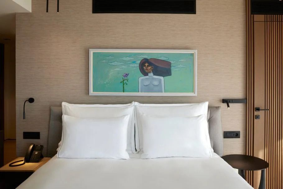 Doppelbett mit weißen Kissen und künstlerischem Gemälde über dem Bett in der Suite.