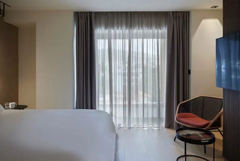 Schlafzimmer mit Vorhängen und natürlichem Licht durch das Fenster in einem Hotel