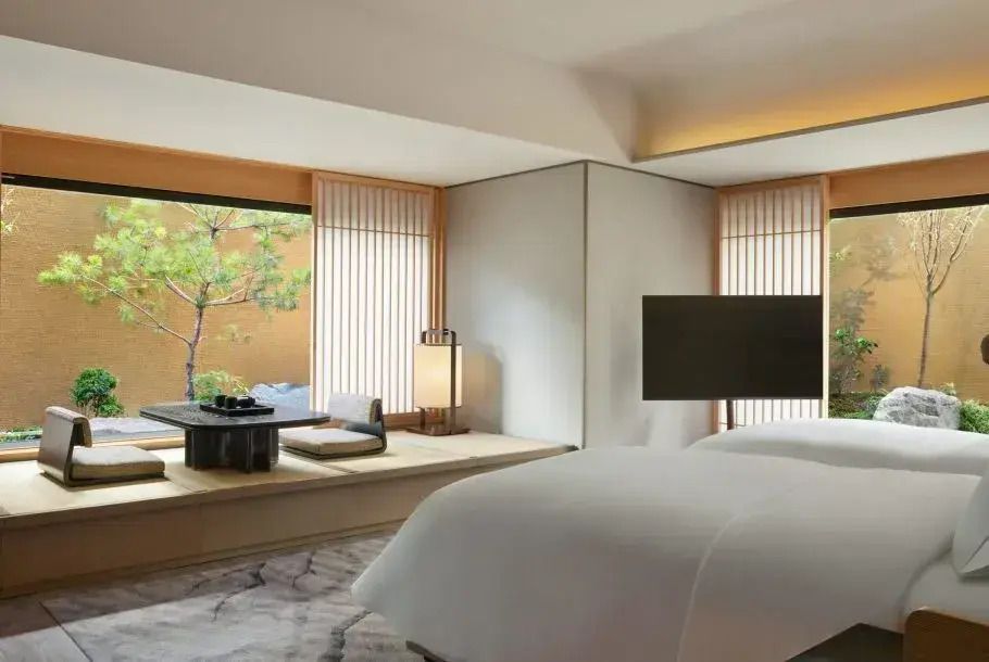 Zimmer mit einem großen Bett und einer schönen Sitzecke mit Gartenblick im Hintergrund