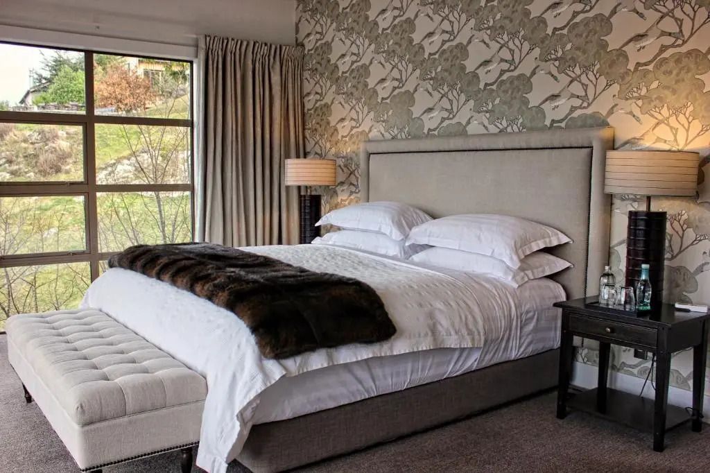 Elegantes Schlafzimmer mit Doppelbett und stilvollen Tapeten im Deluxe Villa Zimmer.
