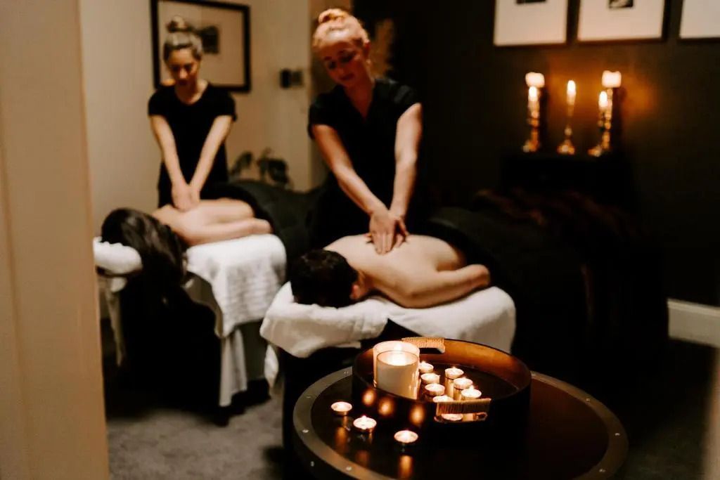 Zwei Personen genießen eine Massage in einem stimmungsvoll beleuchteten Raum.
