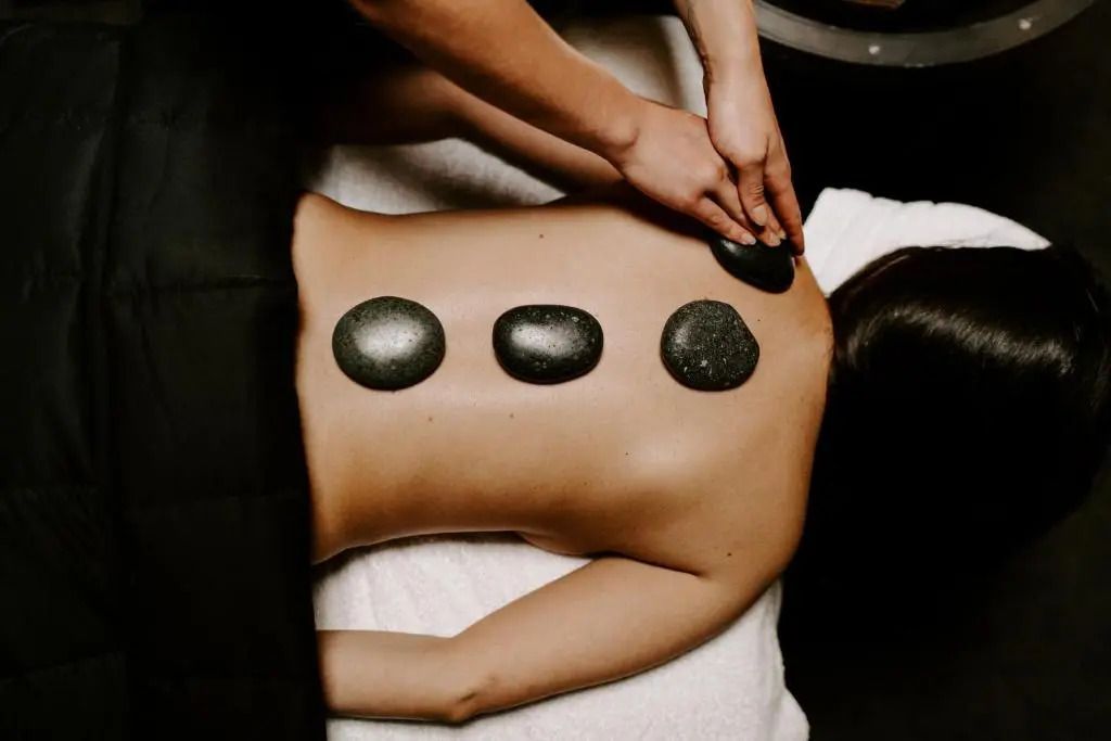 Wellness-Behandlung mit heißen Steinen auf einem Rücken während einer Massage.