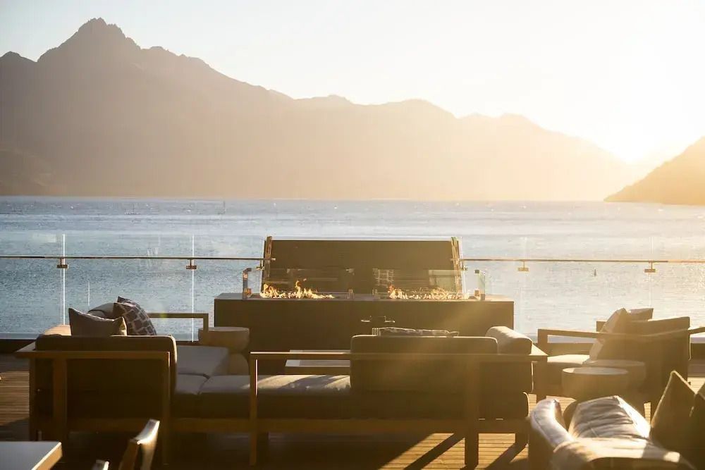 Terrasse mit Sitzbereich und Feuerstelle vor malerischer Berglandschaft und See