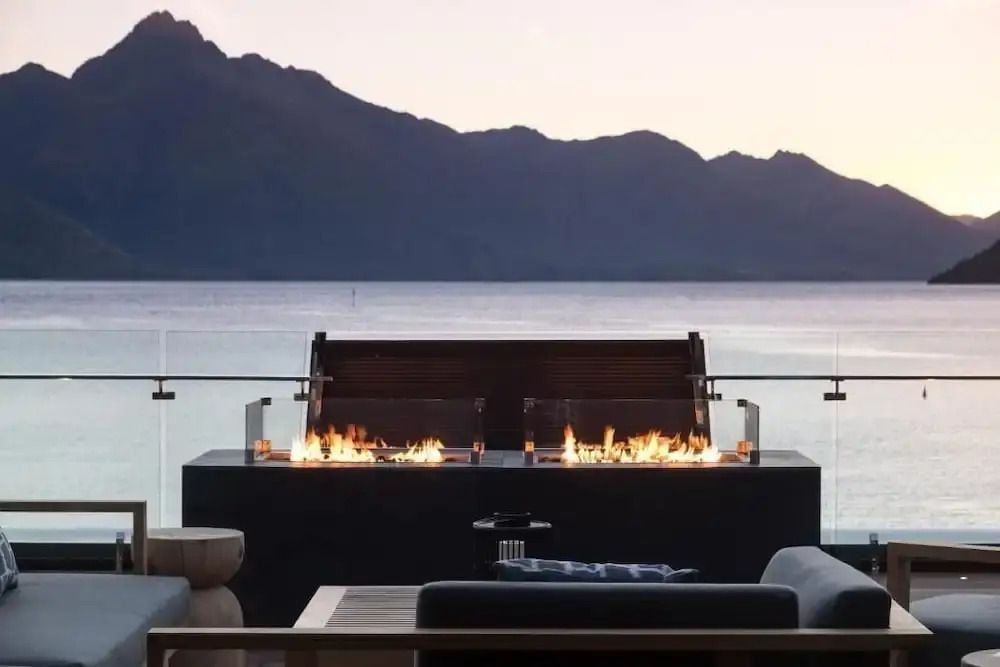 Sonnenuntergang über dem See mit eleganter Feuerstelle auf der Terrasse