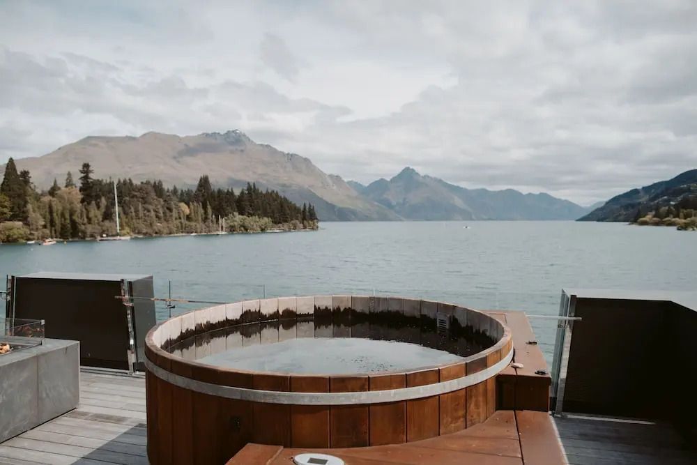 Holz-Whirlpool auf Terrasse mit Blick auf Berge und See