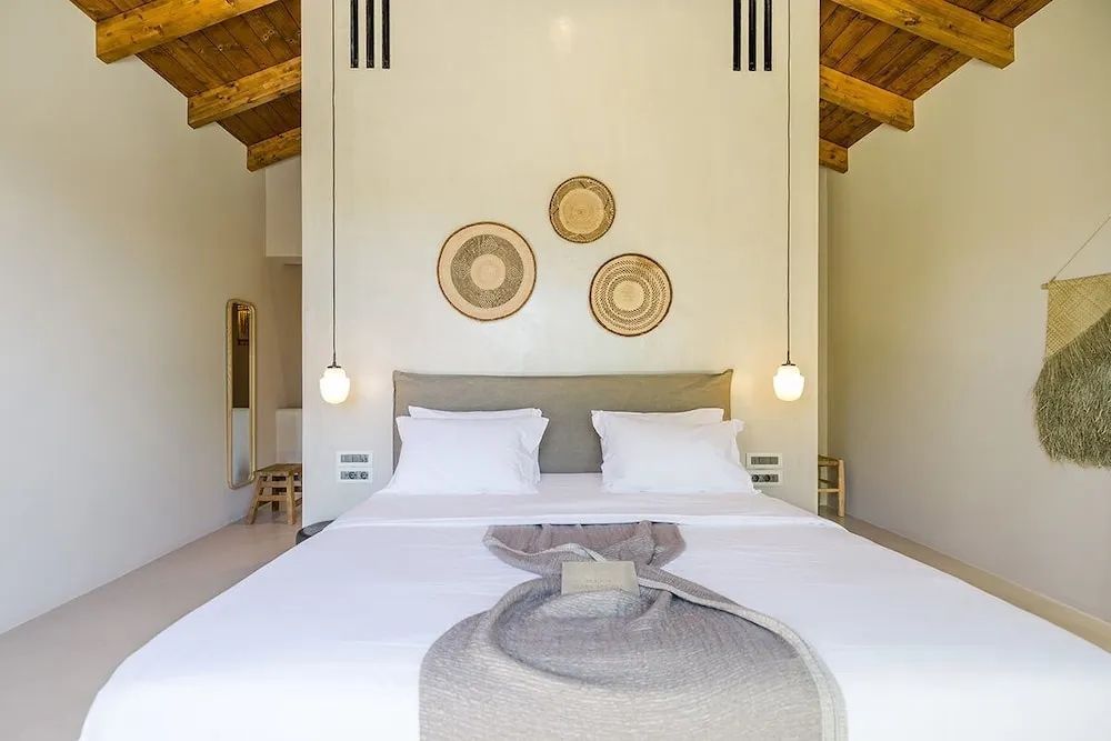 Helles Schlafzimmer mit Doppelbett, verzierten Körben und Holzdecke.
