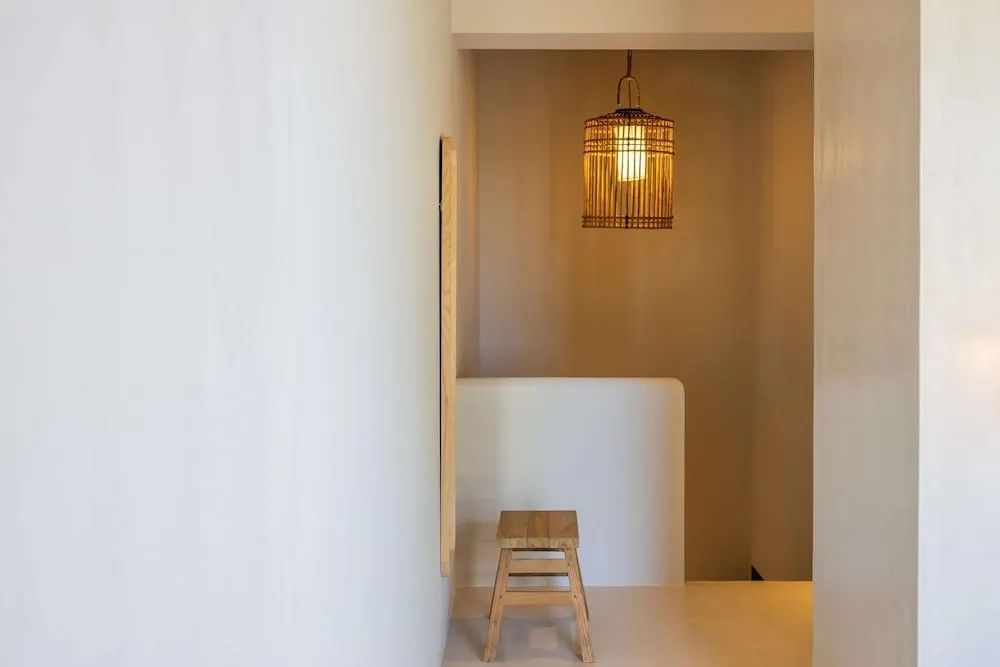 Minimalistischer Flur mit Holzstuhl und gemütlicher Beleuchtung.