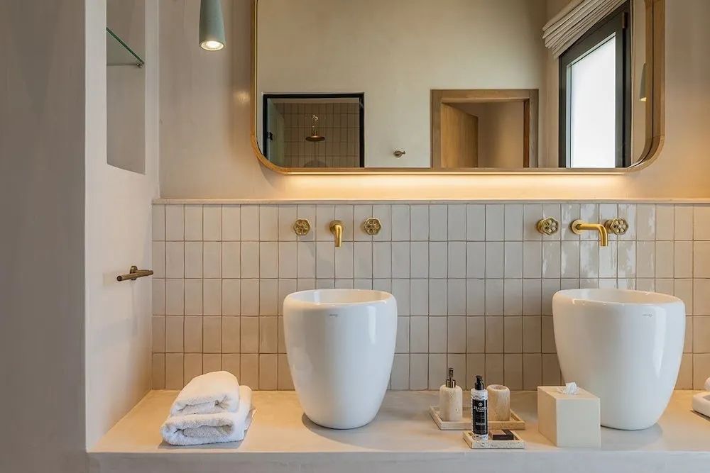 Modernes Badezimmer mit eleganter Waschschale und goldenen Armaturen.