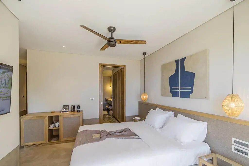 Modernes Schlafzimmer mit Doppelbett, dezenter Kunst und Ventilator.