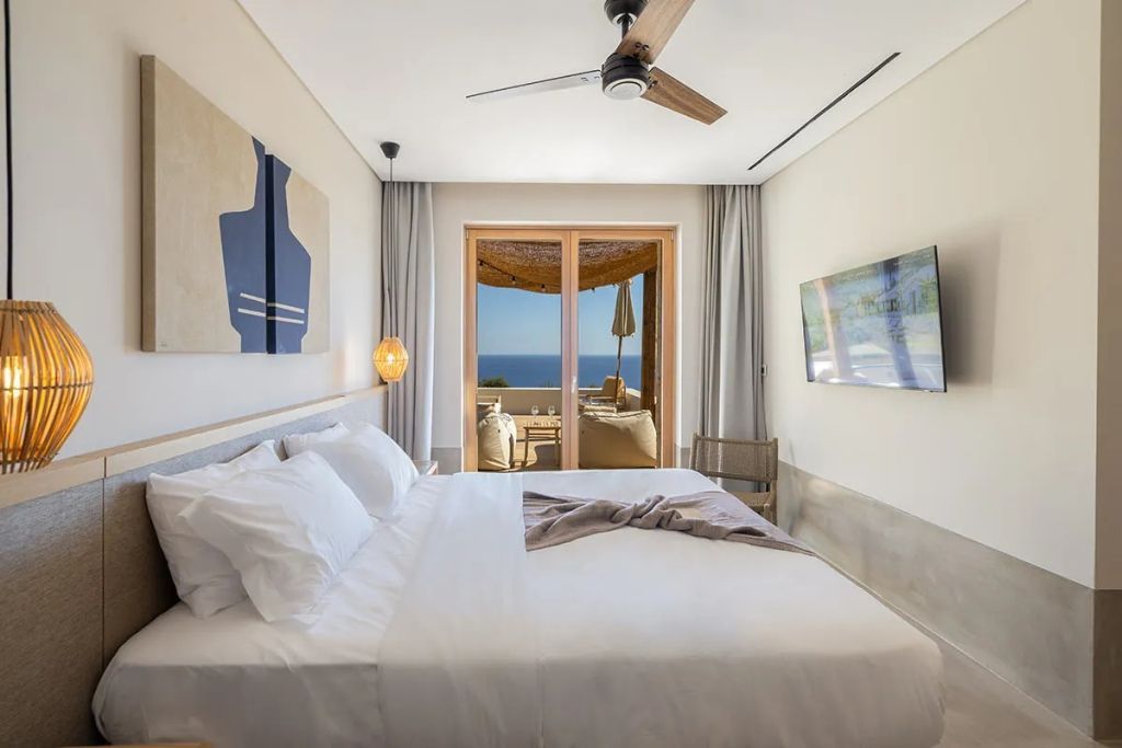 Helles Schlafzimmer der Amos Suite mit Meerblick und Zugang zur Terrasse