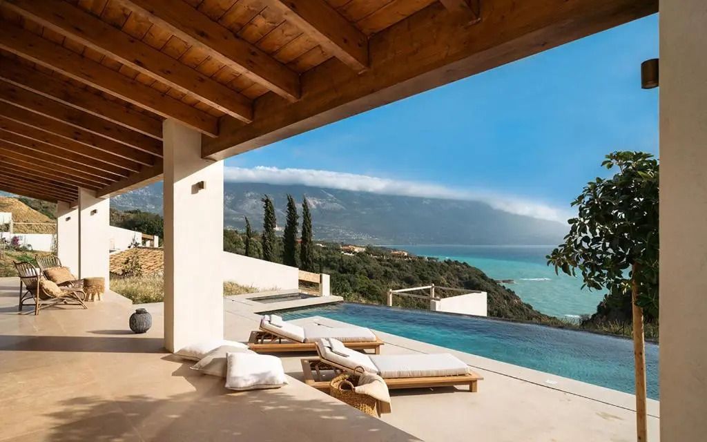 Terrasse mit Liegen am Infinity-Pool und spektakulärem Meerblick