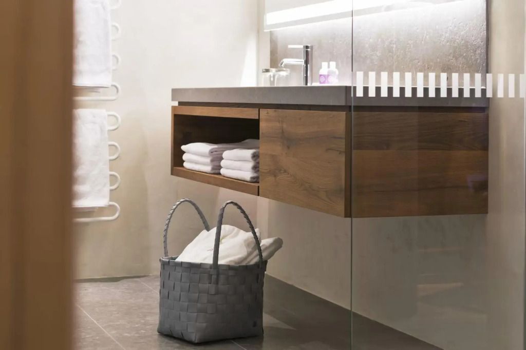 Waschbecken mit dunklem Holzunterschrank und Handtüchern