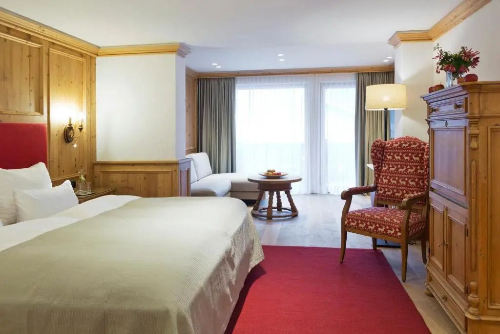 Großer heller Raum mit Doppelbett und gemütlicher Sitzecke im Deluxe Doppelzimmer.