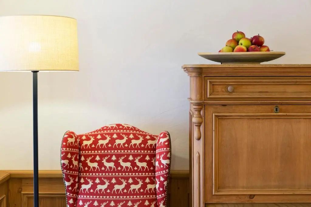 Gemütlicher Sessel mit Hirschmuster neben Holzmöbeln und Obstschale im Zimmer.