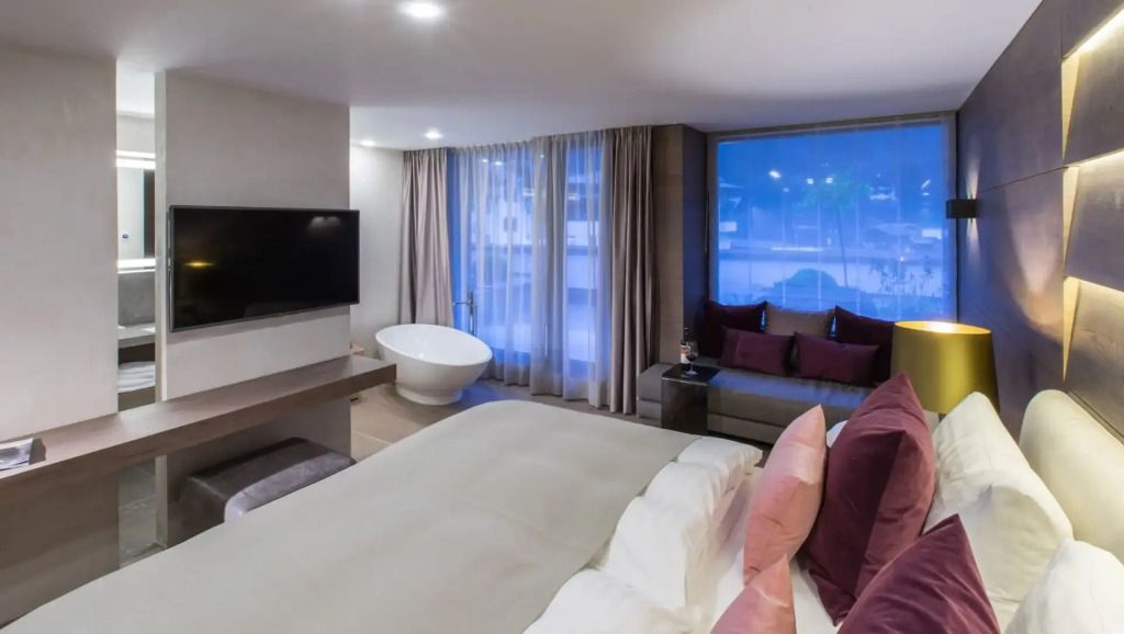 Modernes Premium-Doppelzimmer mit freistehender Badewanne und großen Fenstern.