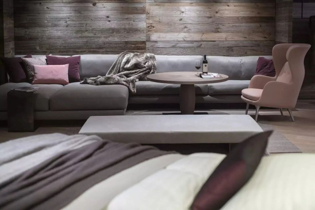 Elegante Sitzecke mit Sofa, Holzwand und stilvollem Couchtisch im Hotelzimmer.