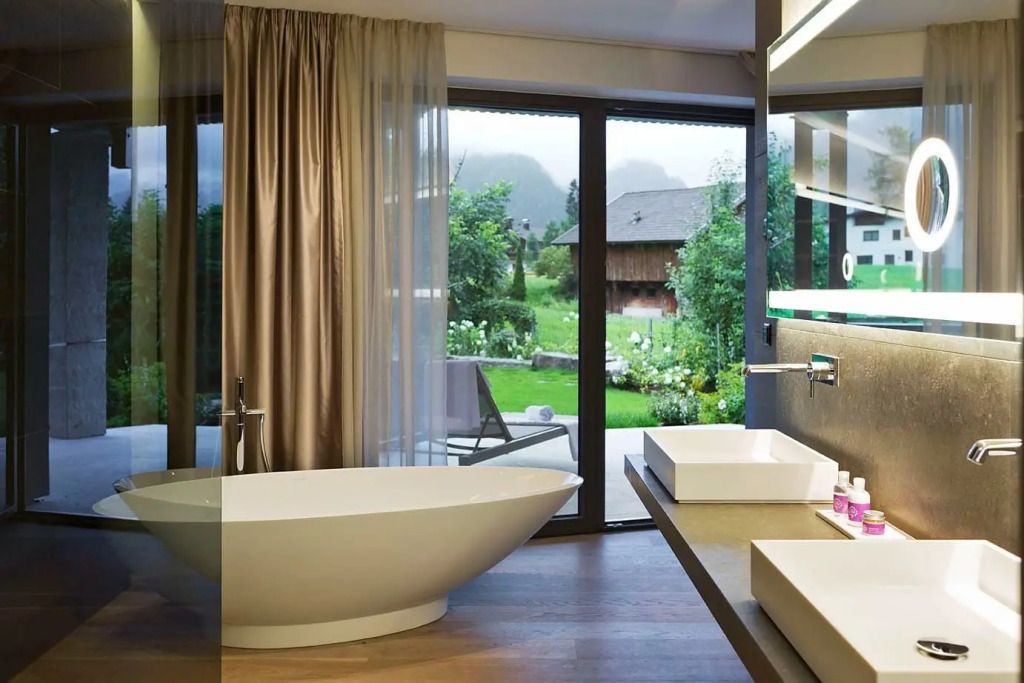 Luxuriöses Badezimmer mit freistehender Badewanne und Aussicht auf Garten.