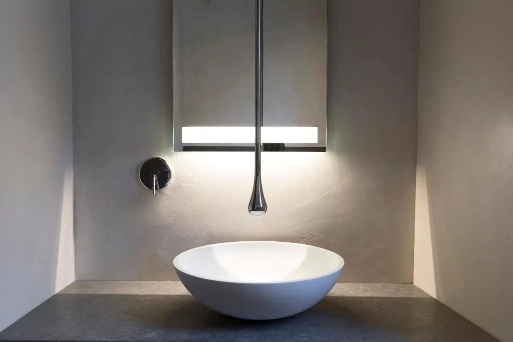 Minimalistisches Badezimmerdesign mit runder Waschschüssel und Beleuchtung
