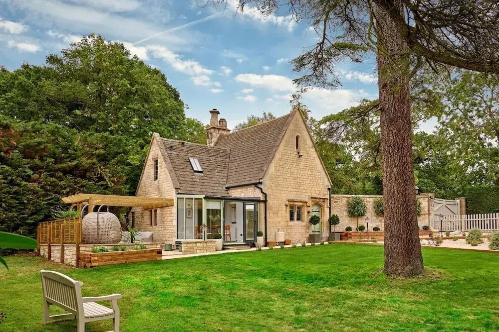 Charmanter Garten mit einer Steinhütte umgeben von Bäumen und Wiese