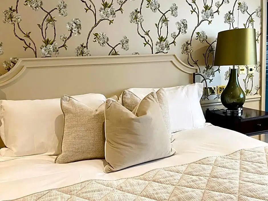 Detailansicht eines gut dekorierten Hotelbetts mit floralem Hintergrund