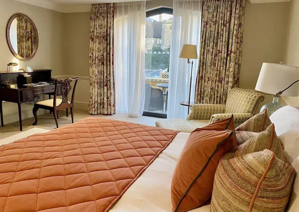 Gemütliches Deluxe Zimmer mit großem Bett, stilvollen Vorhängen und Zugang zu einem Balkon