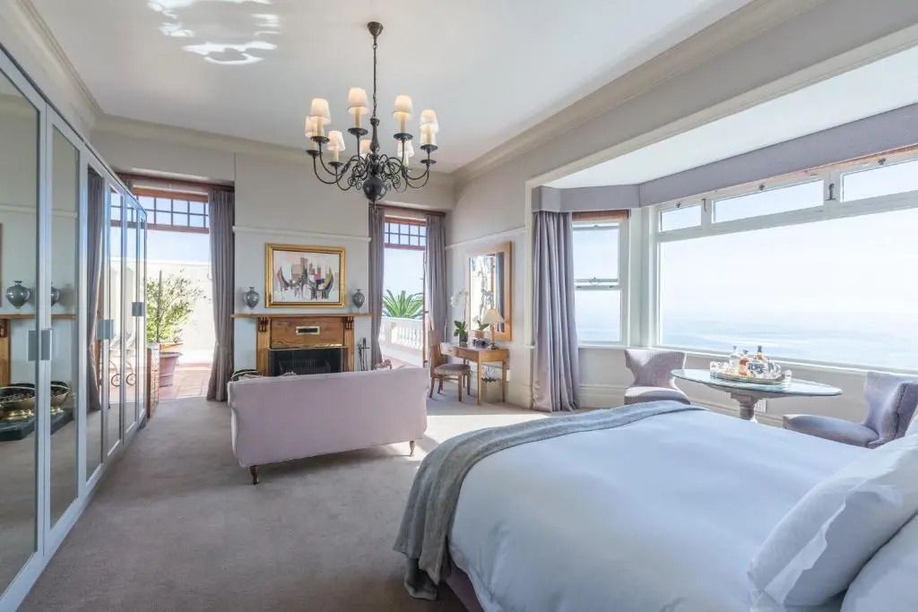 Helles Schlafzimmer mit Kamin und Meerblick, das Eleganz ausstrahlt.