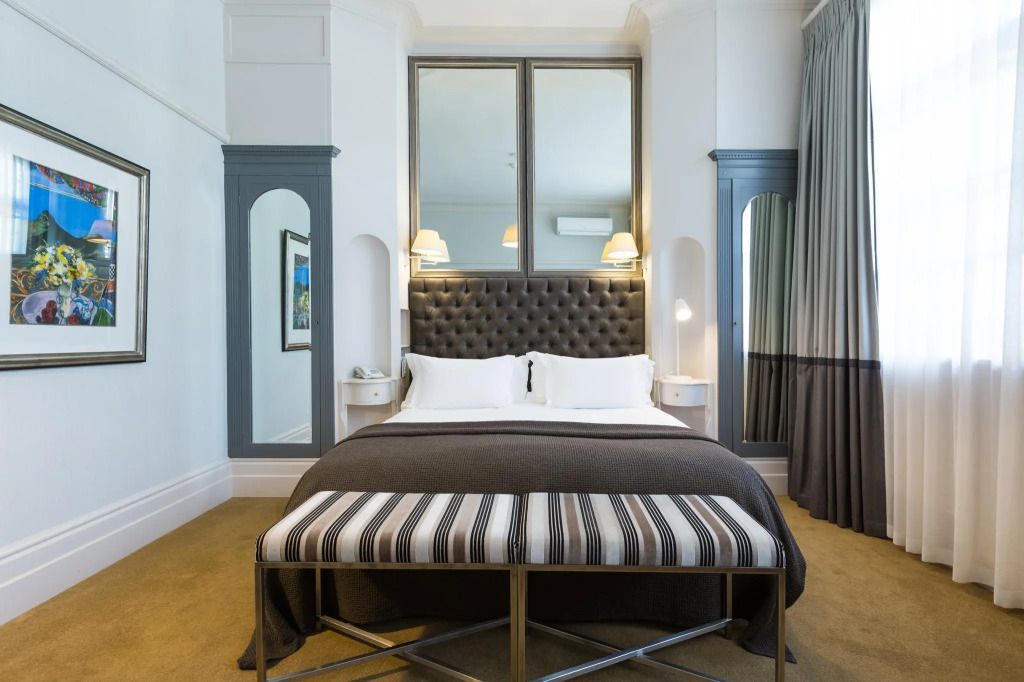 Klassisches Doppelzimmer mit eleganten Spiegeln und Polsterbett in warmen Farben.