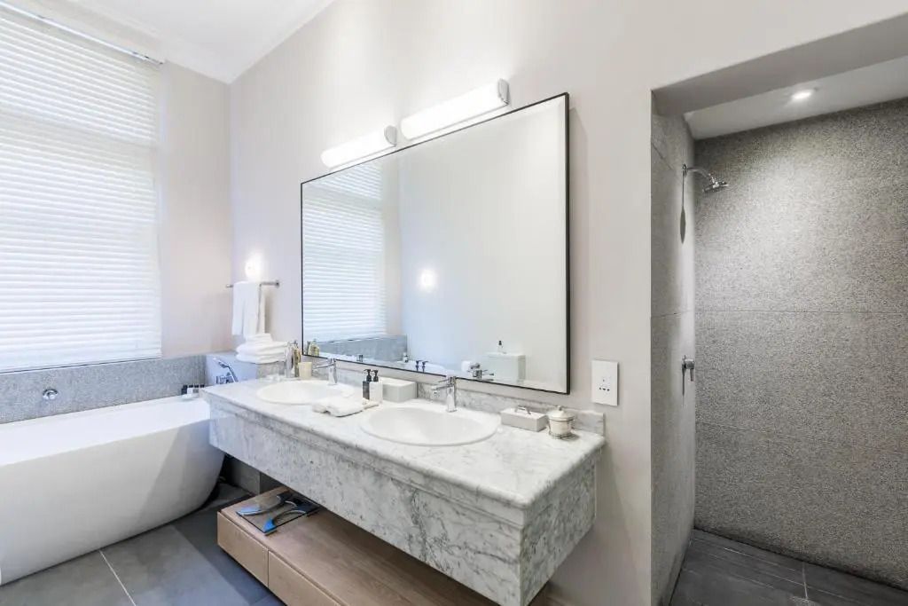 Modernes Badezimmer mit Doppelwaschbecken aus Marmor und Spiegel.