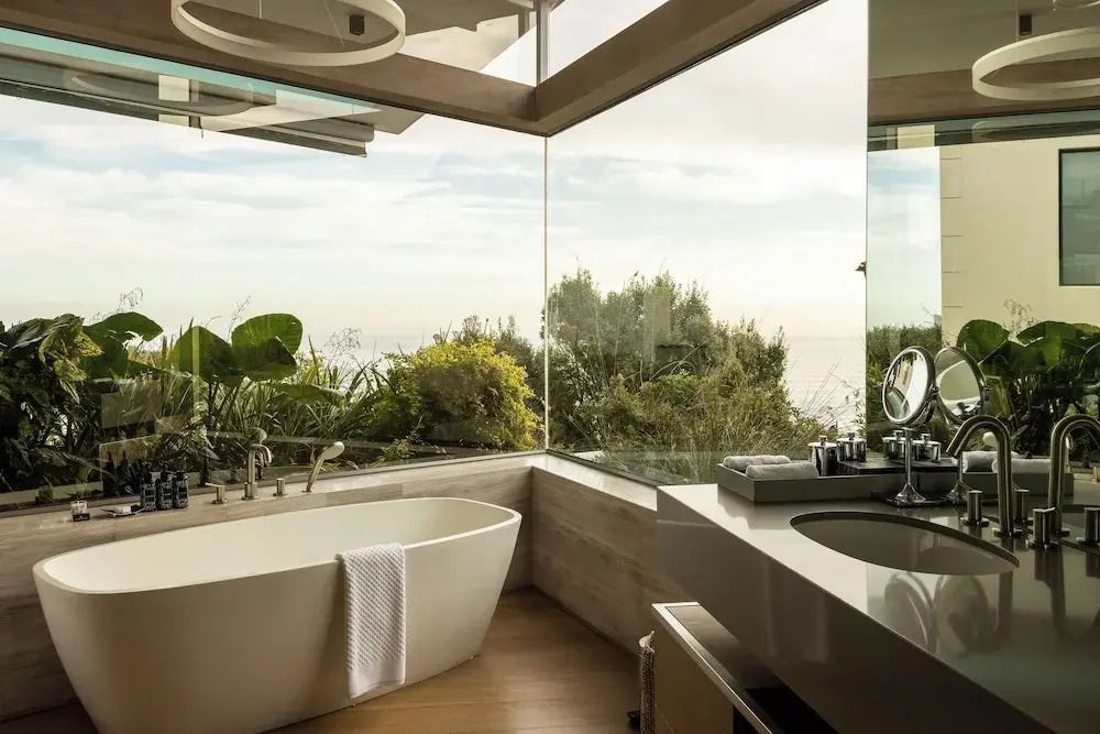 Modernes Badezimmer mit freistehender Badewanne und Blick auf üppiges Grün.