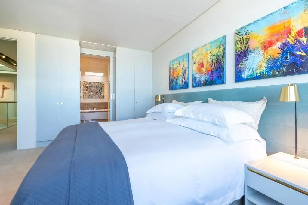 Helles Schlafzimmer mit großem Doppelbett und Kunstgemälden an der Wand.