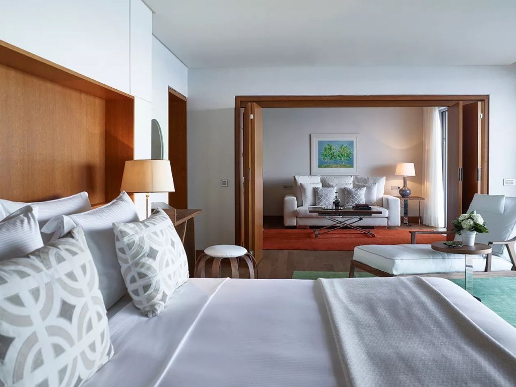 Blick von einem Schlafzimmer in ein stilvolles Wohnzimmer, beide mit moderner Einrichtung.