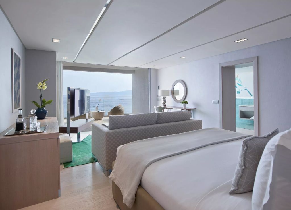 Geräumige Suite mit modernem Design und direktem Meerblick durch große Fenster.
