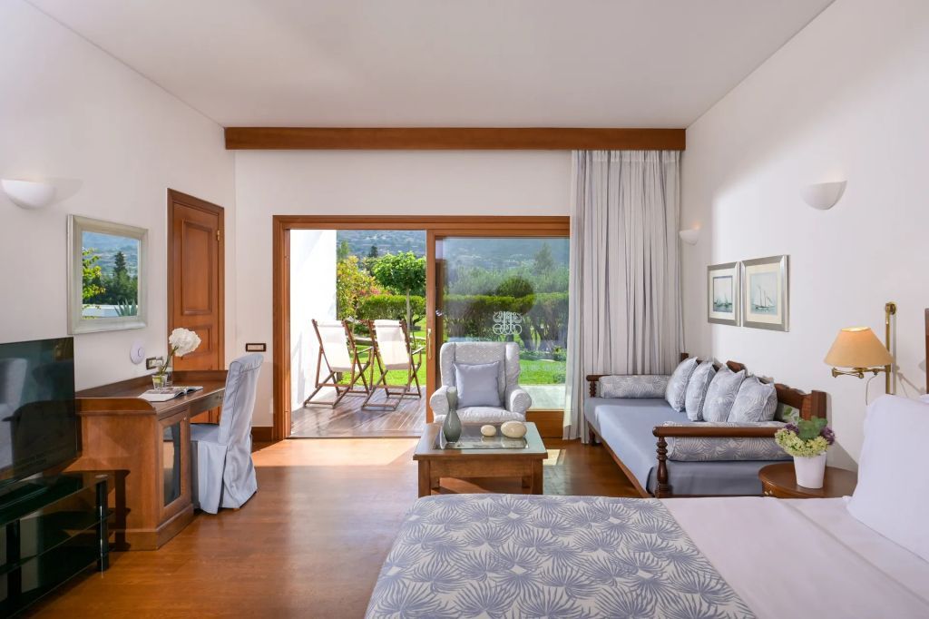 Deluxe Zimmer mit Terrasse und Gartenblick sowie gemütlichen Sitzgelegenheiten.