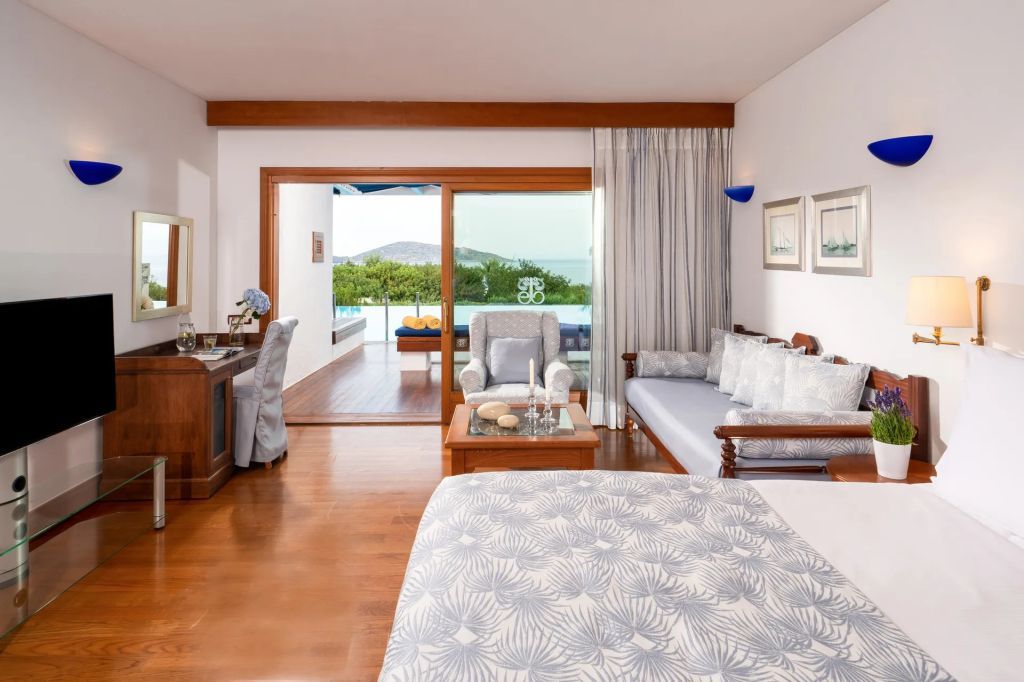 Schlafzimmer mit Holzboden, Schreibtisch und Blick auf Terrasse sowie Meer.