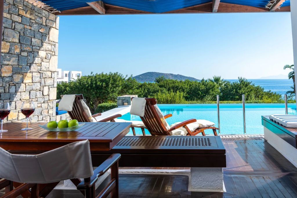 Terrasse mit Liegestühlen und direktem Zugang zu einem Pool mit Meerblick.