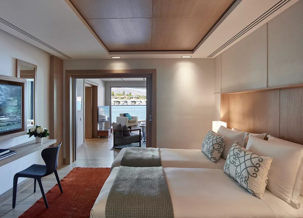 Doppelbett-Suite mit eleganten Kissen, modern eingerichteter Raum und Balkon mit Meerblick.