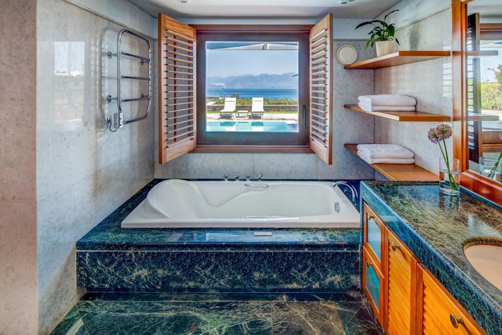 Luxuriöses Badezimmer mit Fenster zum Pool und Meerblick