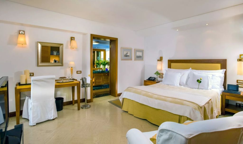 Elegantes Zimmer mit Doppelbett und hellem Interieur. Zugang zu einem Badezimmer.