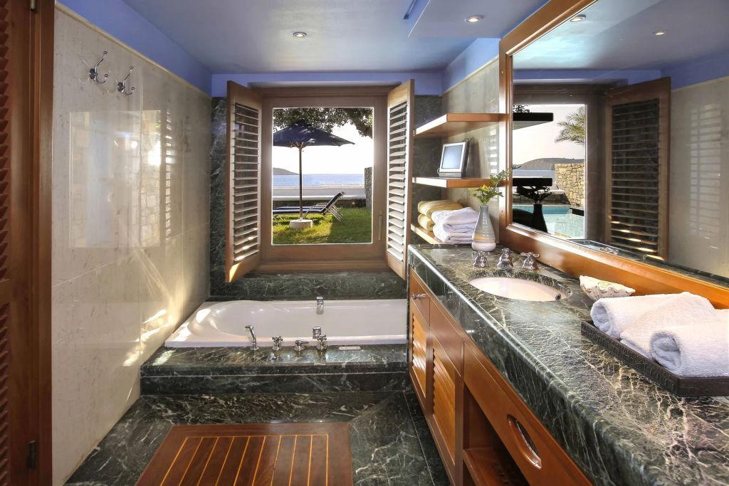Badezimmer mit Jacuzzi und Ausblick auf den Poolbereich und das Meer