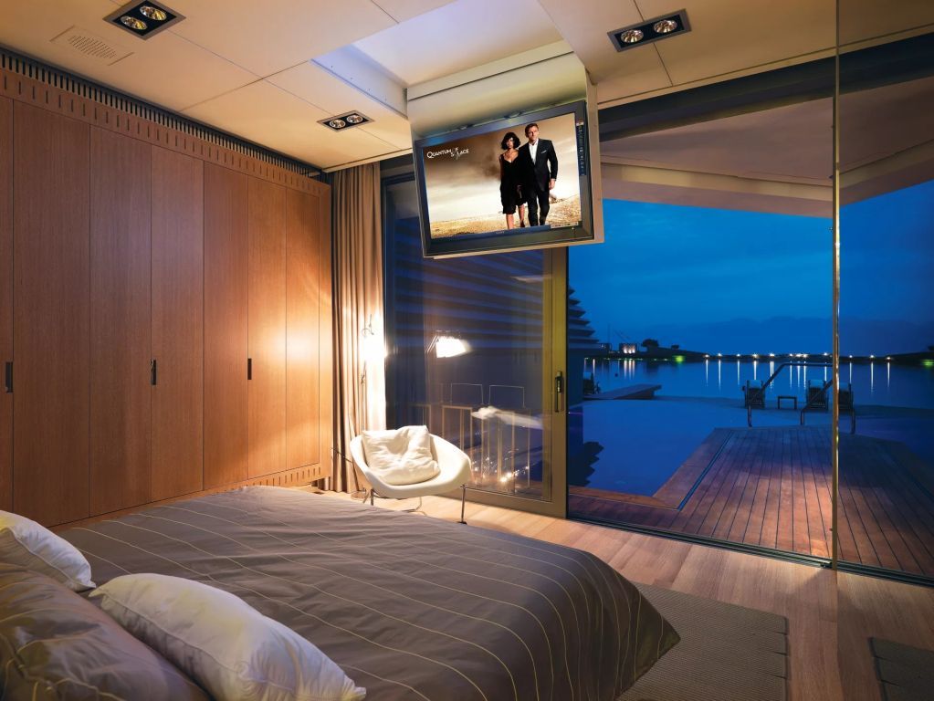 Luxuriöses Schlafzimmer mit Blick auf den privaten beheizten Pool und das Meer bei Nacht