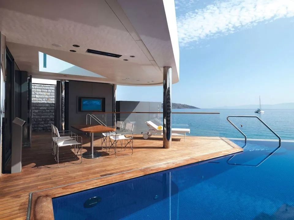 Private Terrasse mit Pool und entspannter Sitzgelegenheit direkt am Meer bei strahlendem Sonnenschein