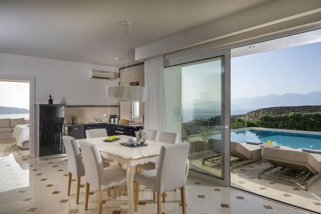 Essbereich neben offenem Zugang zur Terrasse mit Pool und Meeresblick.