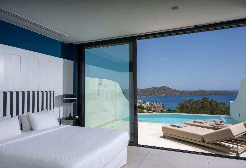 Modernes Hotelzimmer mit Blick auf das Meer und Infinity-Pool durch große Glastüren