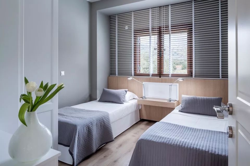 Zweibettzimmer mit moderner Einrichtung und großen Fenstern in einer Villa.