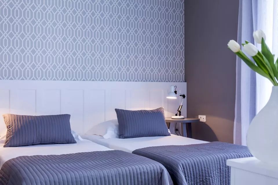 Schlafzimmer mit zwei Einzelbetten und stilvollem Design in neutralen Tönen.